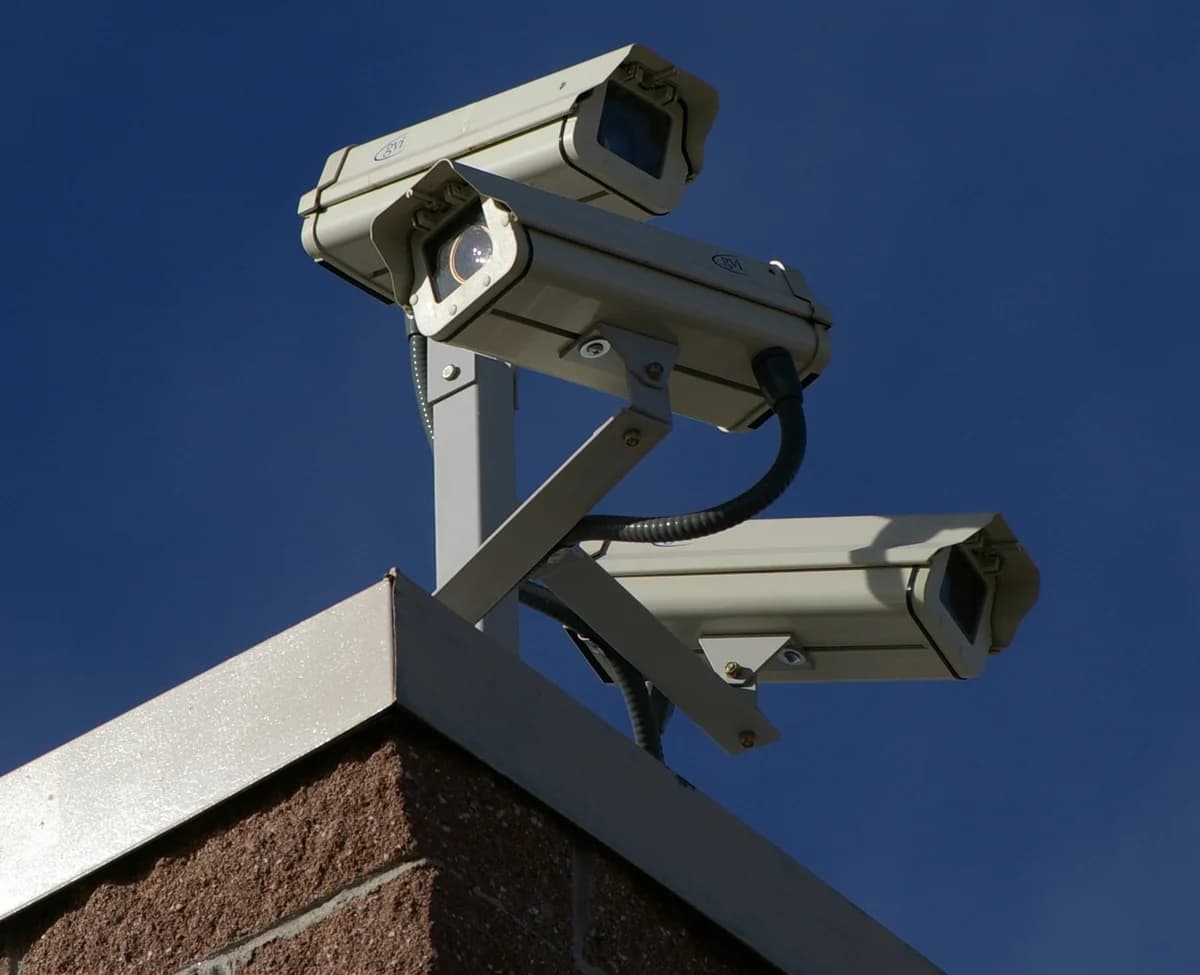 Three surveillance cameras mounted on the corner of a building